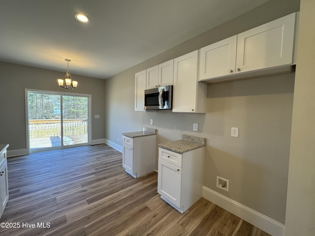 kitchen with white cabinetry, an inviting chandelier, pendant lighting, and wood-type flooring