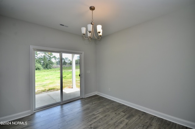 empty room with dark wood-style floors, baseboards, visible vents, and a notable chandelier