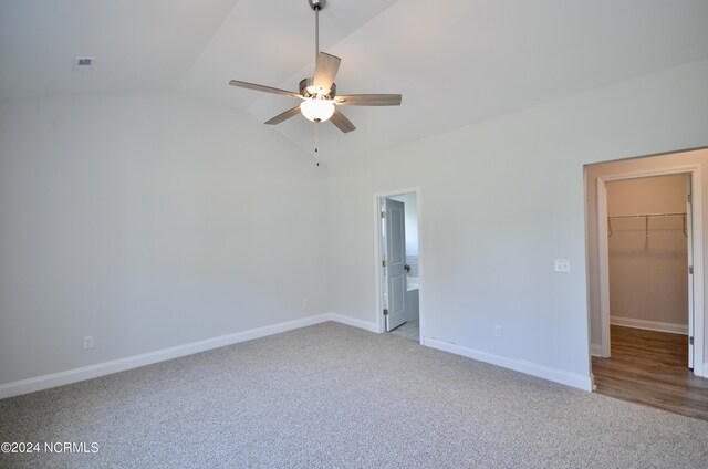 unfurnished bedroom with visible vents, baseboards, vaulted ceiling, a spacious closet, and carpet