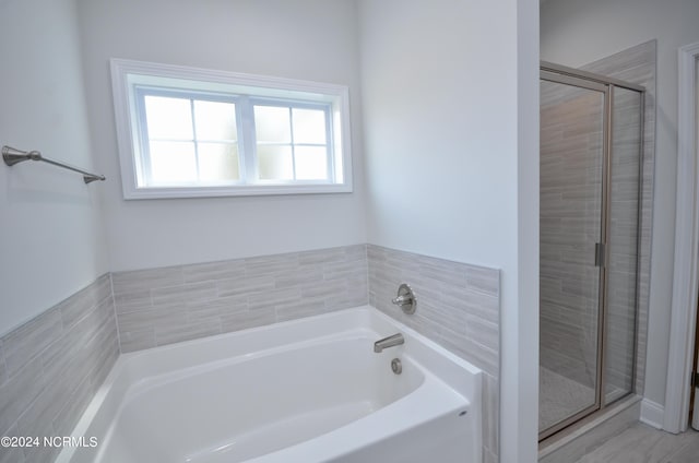 bathroom featuring a garden tub and a shower stall