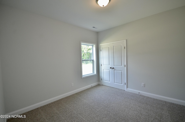 empty room featuring light carpet, visible vents, and baseboards