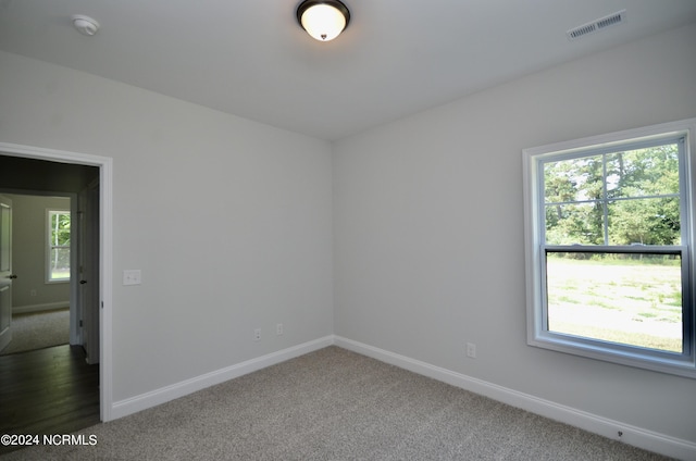 carpeted spare room with visible vents and baseboards