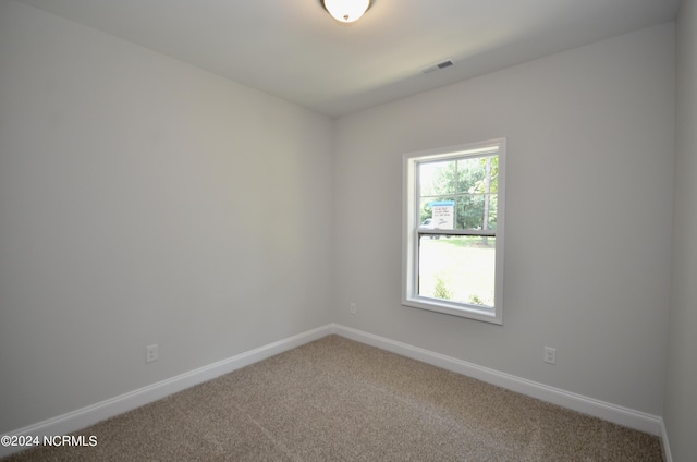 carpeted spare room featuring baseboards and visible vents