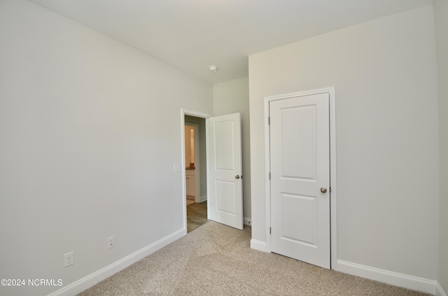 unfurnished bedroom with light colored carpet and baseboards