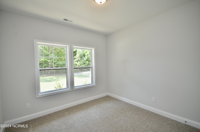 unfurnished room with carpet, visible vents, and baseboards