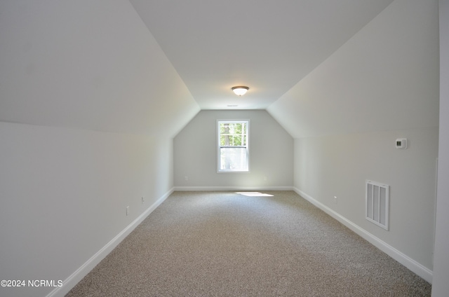 additional living space featuring lofted ceiling, visible vents, light carpet, and baseboards