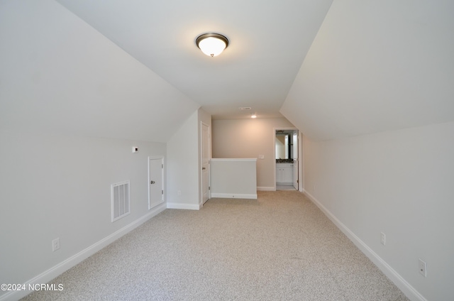 bonus room with light carpet, lofted ceiling, visible vents, and baseboards