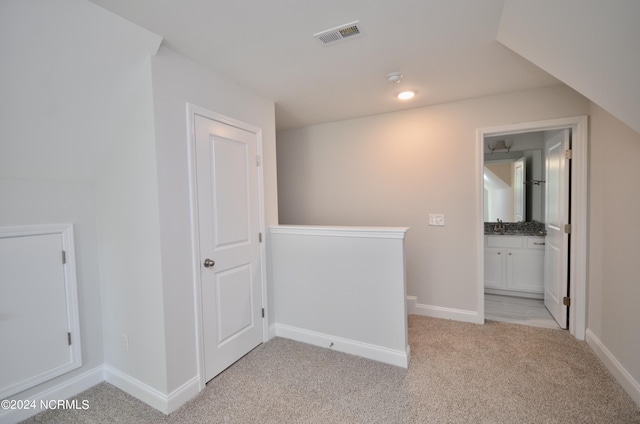 corridor with light carpet, visible vents, and baseboards