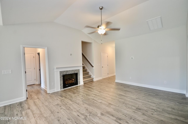 unfurnished living room with a fireplace, lofted ceiling, ceiling fan, wood finished floors, and baseboards