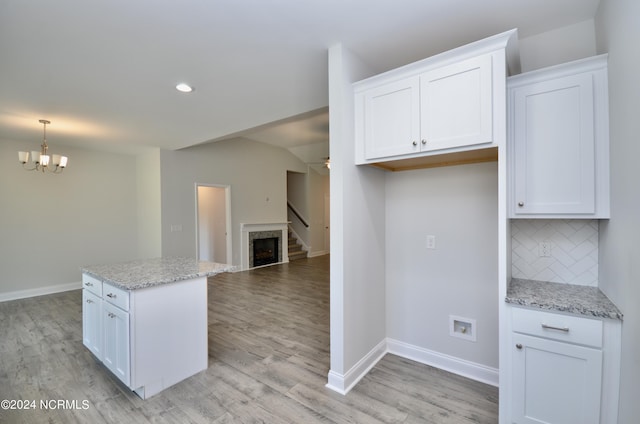 kitchen featuring light wood-type flooring, decorative backsplash, white cabinetry, and a center island