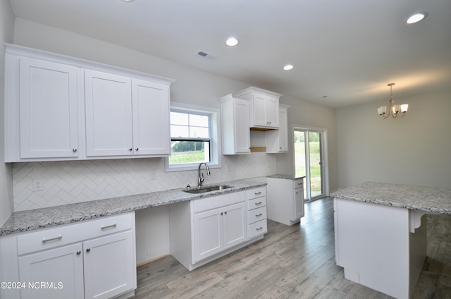 kitchen featuring tasteful backsplash, recessed lighting, light wood-style flooring, white cabinetry, and a sink