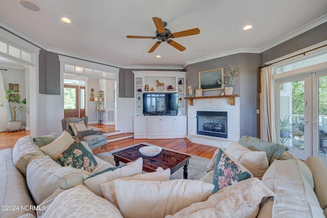 living room with ceiling fan, light wood-type flooring, and ornamental molding