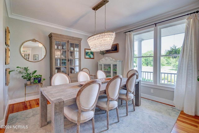 dining area featuring a chandelier, light wood-type flooring, and ornamental molding