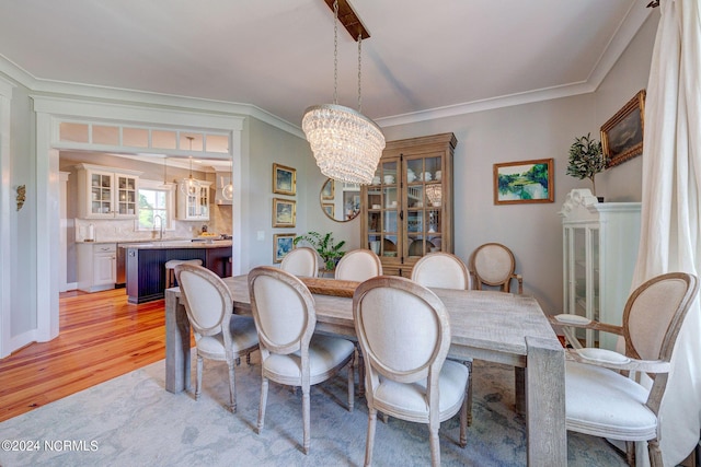 dining area featuring sink, light hardwood / wood-style flooring, crown molding, and a notable chandelier