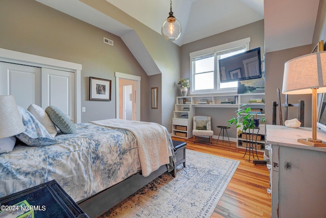 bedroom with hardwood / wood-style floors, a closet, and lofted ceiling