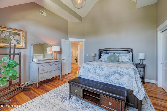 bedroom with light hardwood / wood-style floors and high vaulted ceiling