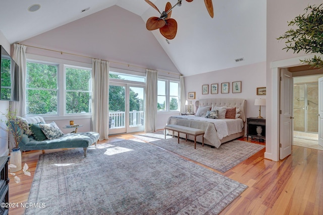 bedroom with ceiling fan, light hardwood / wood-style flooring, high vaulted ceiling, ensuite bathroom, and access to outside