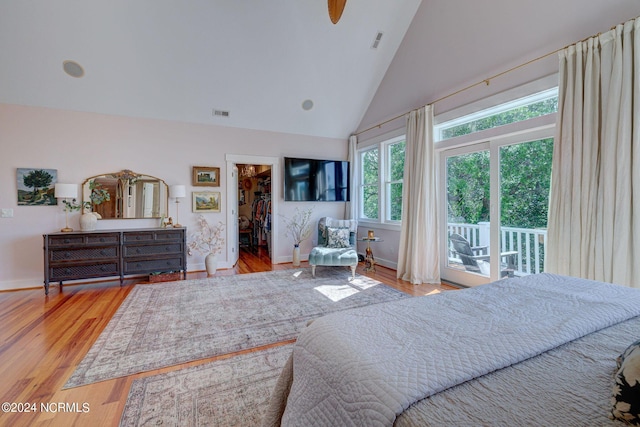 bedroom with access to exterior, a walk in closet, light wood-type flooring, and a closet