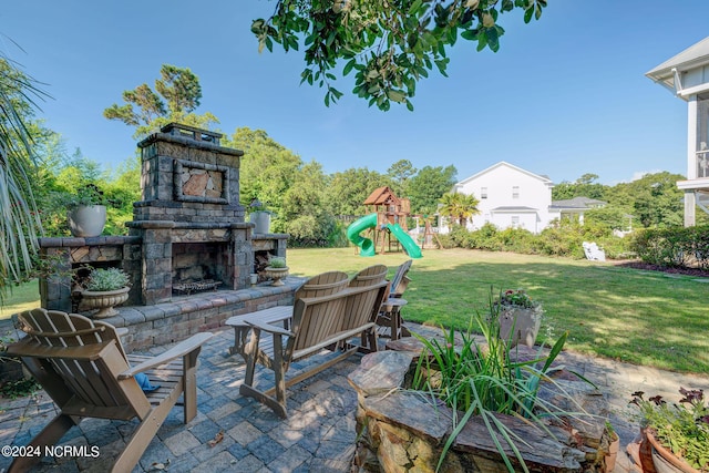 view of patio / terrace with an outdoor stone fireplace and a playground