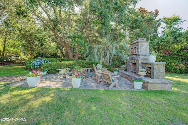 view of yard featuring an outdoor stone fireplace and a patio