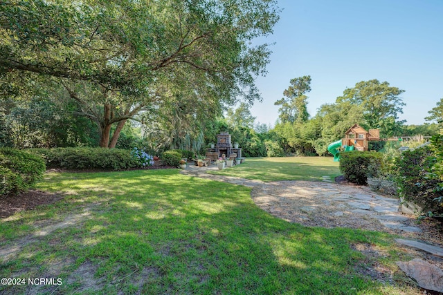 view of yard featuring a playground and an outdoor stone fireplace