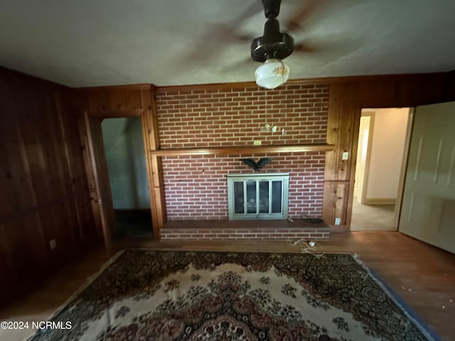 unfurnished living room with wooden walls, light hardwood / wood-style floors, and a brick fireplace