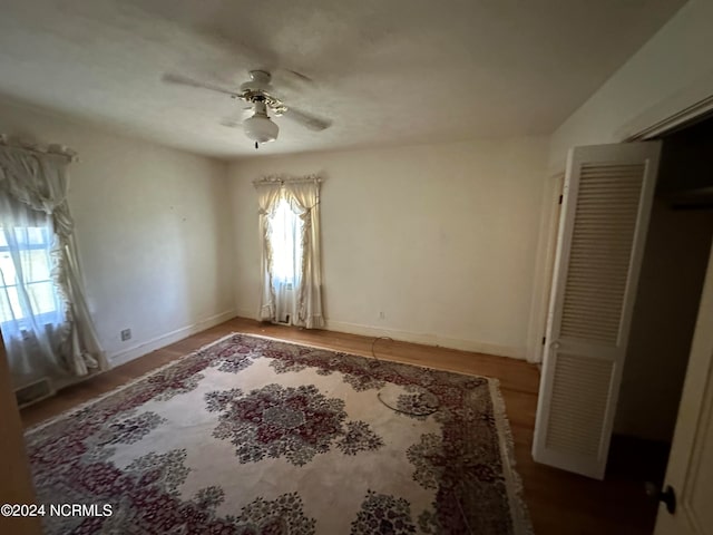 unfurnished bedroom with multiple windows, ceiling fan, and wood-type flooring