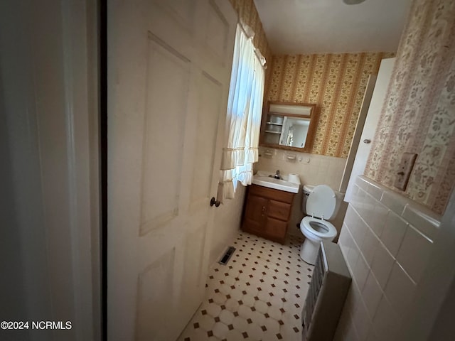 bathroom featuring tile patterned floors, vanity, tile walls, and toilet