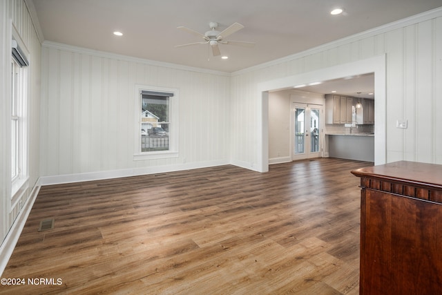 unfurnished living room featuring crown molding, hardwood / wood-style floors, ceiling fan, and a wealth of natural light