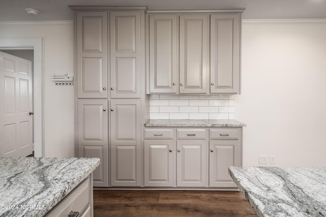 kitchen with crown molding, light stone countertops, dark hardwood / wood-style floors, and tasteful backsplash