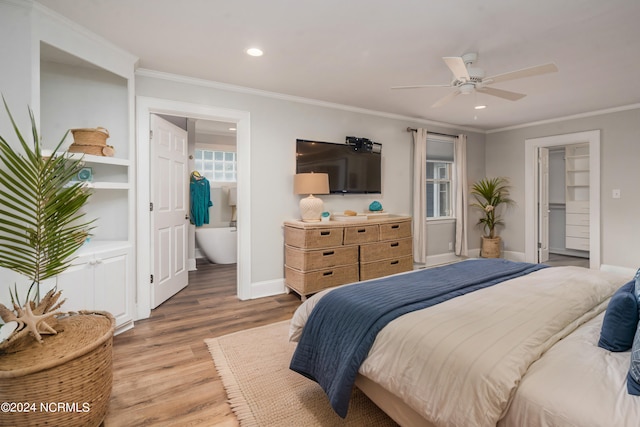 bedroom featuring wood-type flooring, a walk in closet, ceiling fan, connected bathroom, and ornamental molding