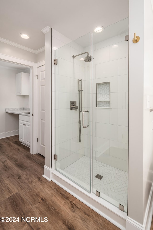 bathroom with vanity, ornamental molding, a shower with shower door, and hardwood / wood-style floors