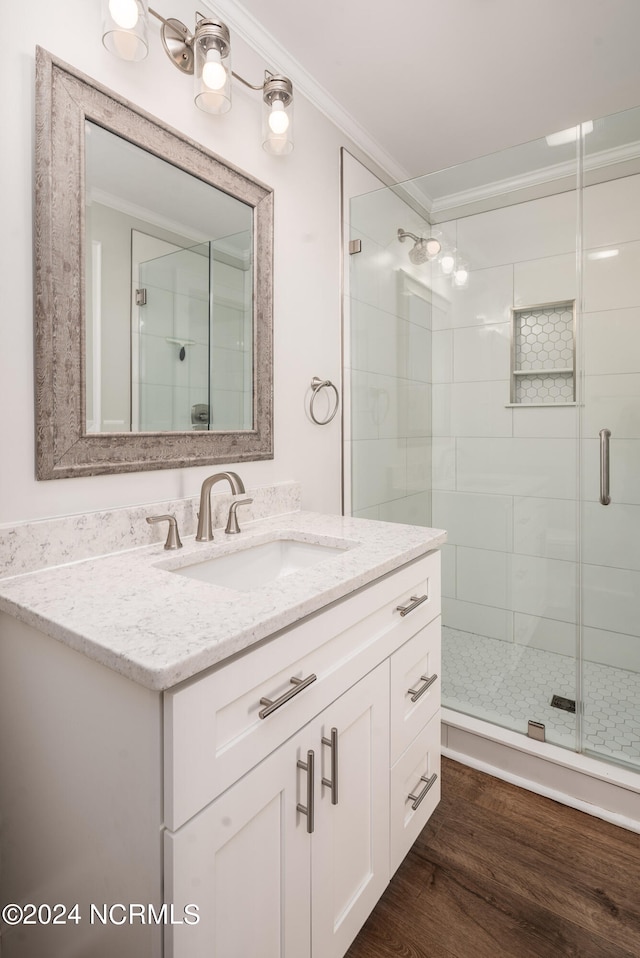 bathroom with vanity, hardwood / wood-style floors, a shower with shower door, and ornamental molding