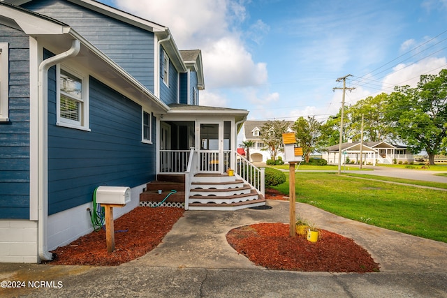 property entrance featuring a lawn and a porch