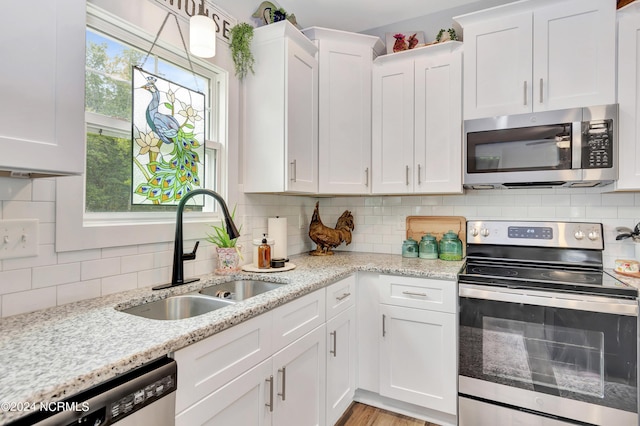 kitchen featuring stainless steel appliances, white cabinetry, sink, and decorative backsplash