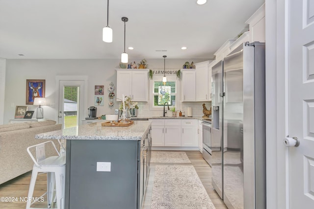 kitchen featuring white cabinetry, a center island, appliances with stainless steel finishes, a kitchen breakfast bar, and pendant lighting