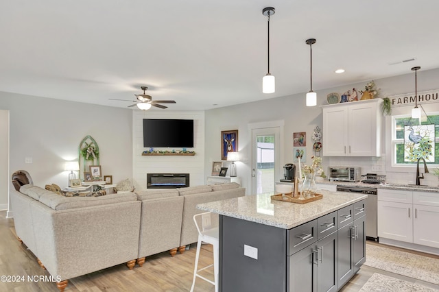 kitchen with white cabinetry, stainless steel dishwasher, a center island, and sink