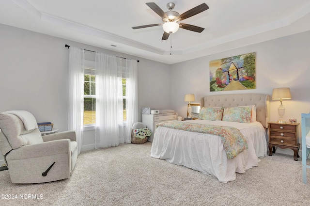 carpeted bedroom featuring ceiling fan and a tray ceiling