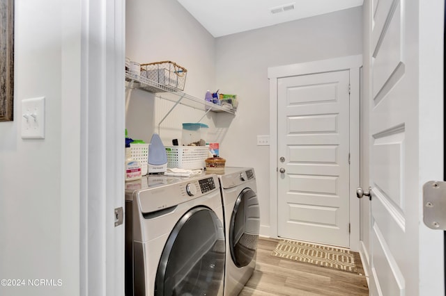 laundry area with washing machine and clothes dryer and light hardwood / wood-style floors