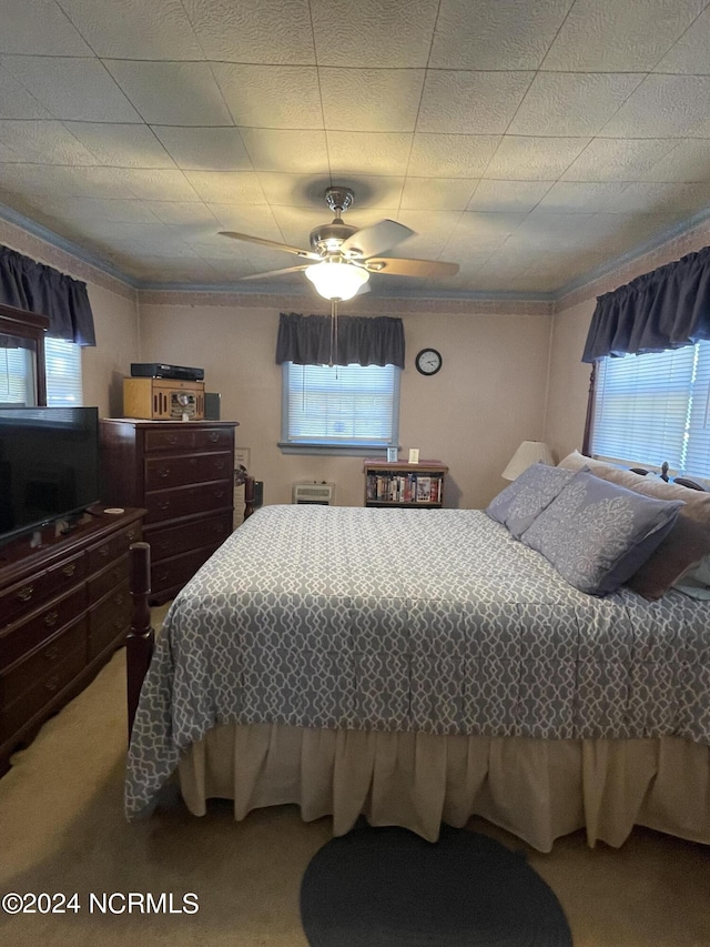 carpeted bedroom with a ceiling fan and crown molding