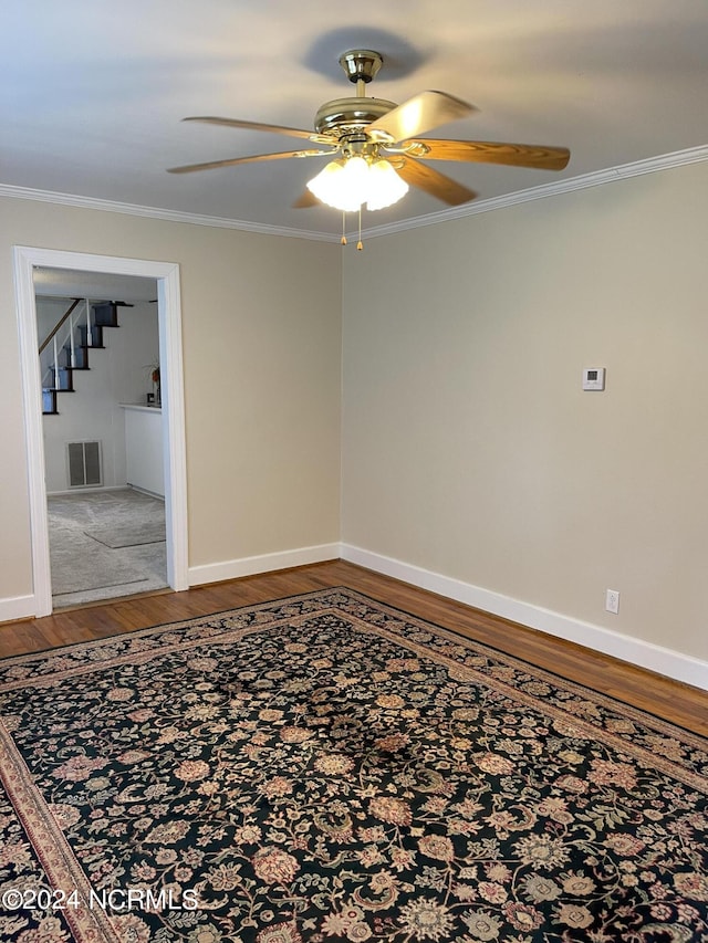 unfurnished room with baseboards, wood finished floors, visible vents, and crown molding