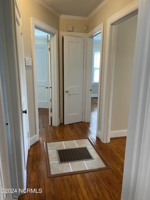 corridor featuring baseboards, visible vents, wood finished floors, and ornamental molding