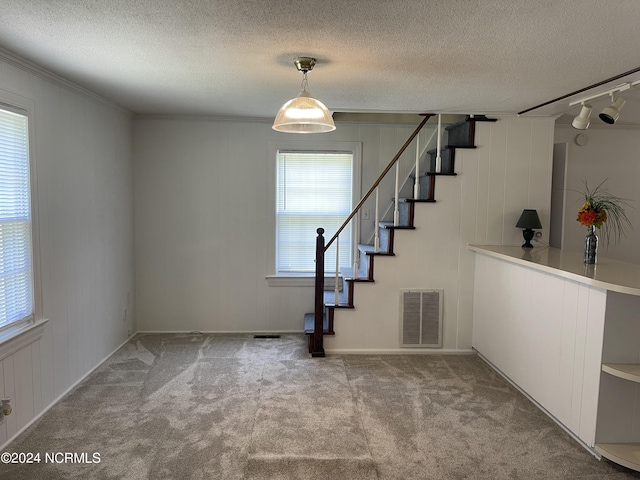 foyer entrance featuring visible vents, a textured ceiling, carpet flooring, and stairs