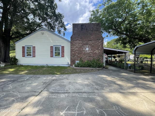 view of home's exterior featuring driveway, a yard, and an attached carport