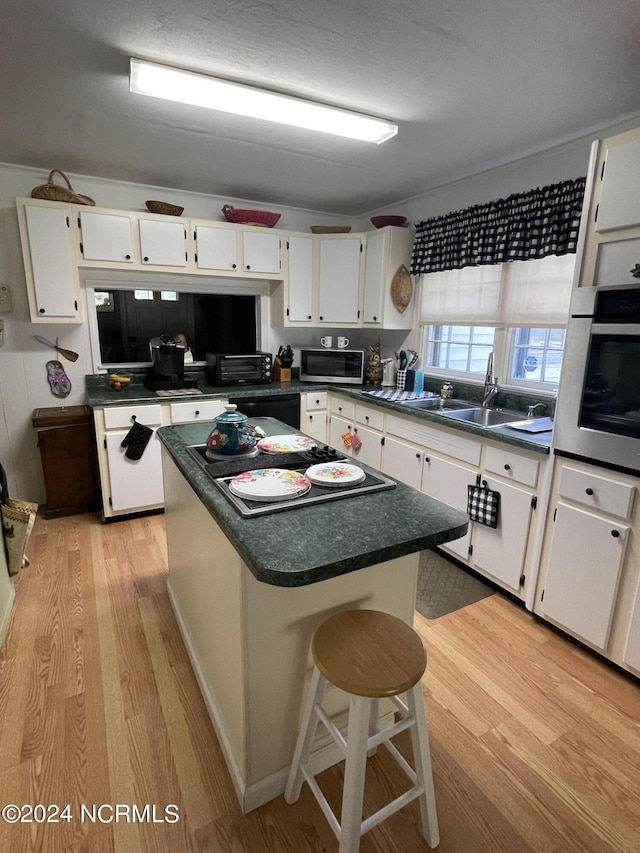 kitchen with light wood finished floors, appliances with stainless steel finishes, and dark countertops