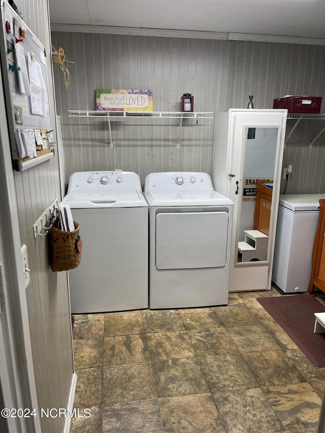 laundry room featuring laundry area, wood walls, and separate washer and dryer