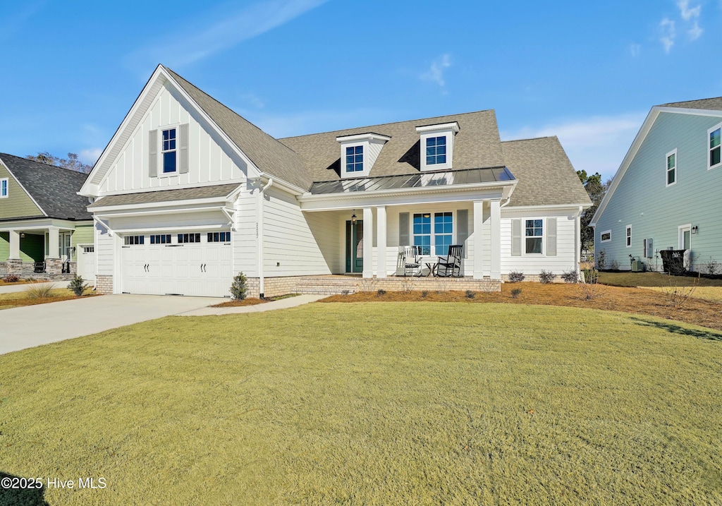 craftsman-style house with a standing seam roof, a front lawn, a porch, and concrete driveway