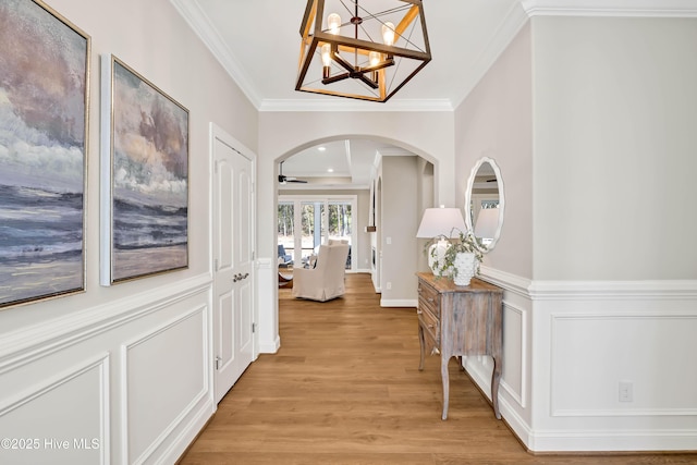 corridor with hardwood / wood-style flooring, ornamental molding, and an inviting chandelier