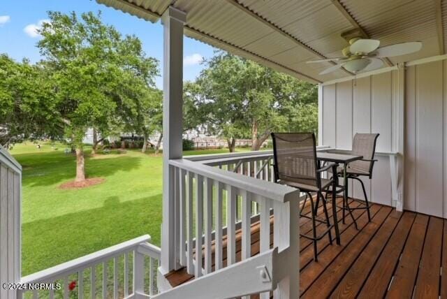 wooden deck featuring a lawn and a ceiling fan