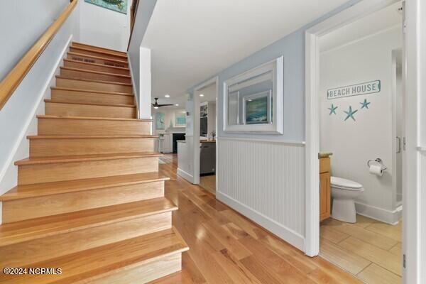 stairs with a fireplace, a skylight, wood finished floors, and a ceiling fan